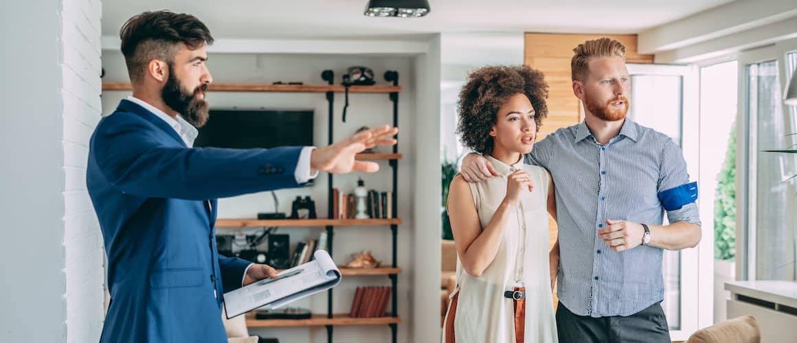 RHB Assets From IGX: Young couple looking at a house with real estate agent, alternative angle