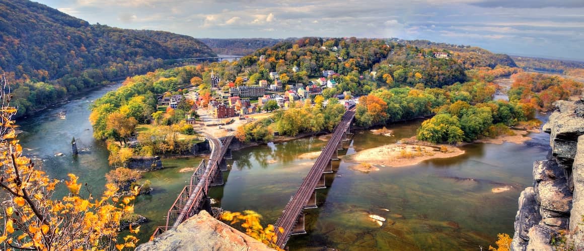 RHB Assets From IGX: A scenic view of Harpers Ferry, West Virginia, with autumn foliage and the Potomac River in the foreground.