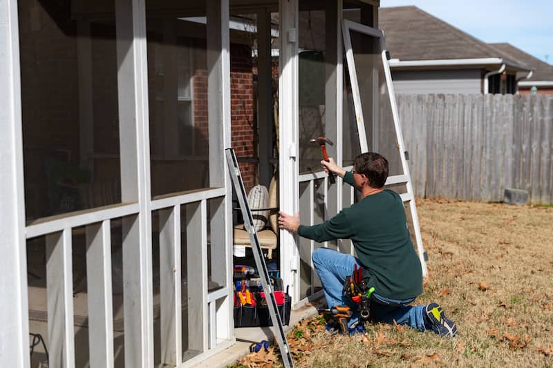 Homeowner reinstalling a newly screened screen door.