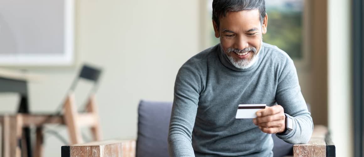 Image of man smiling and looking down at credit card.