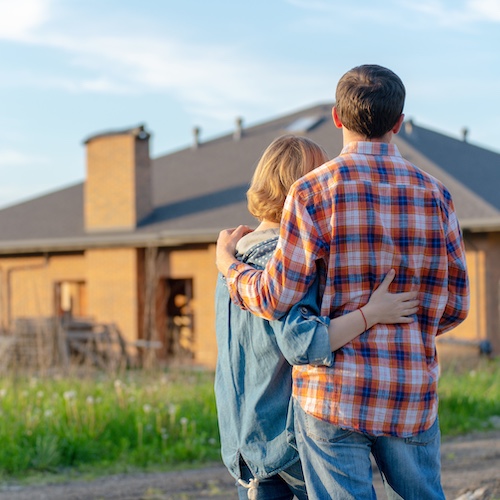 Couple embracing while looking at home.