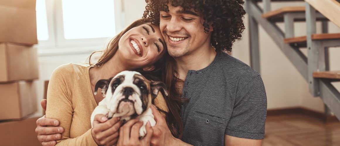 Young couple smiling and holding a dog.