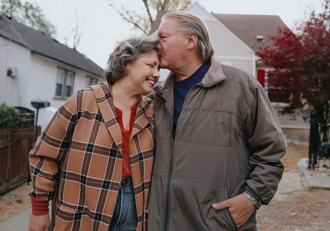 Older couple standing together outside a home.
