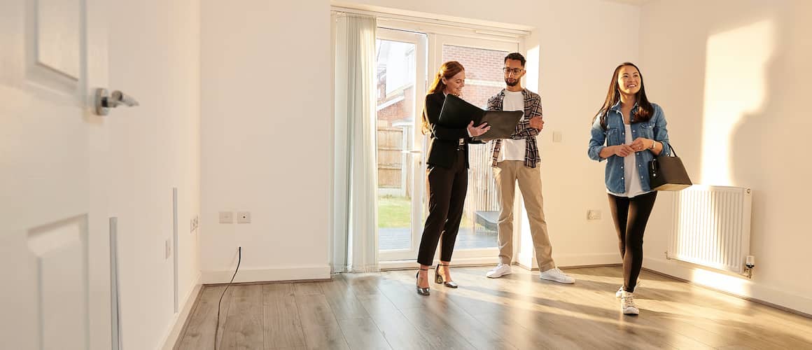 A realtor showing a property to a couple and describing its features.