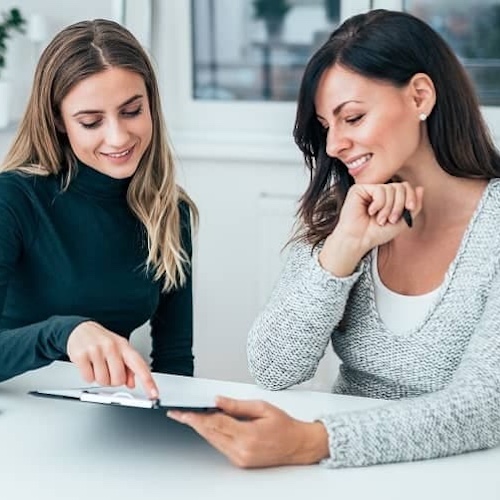 Two women going over paperwork in an office setting.
