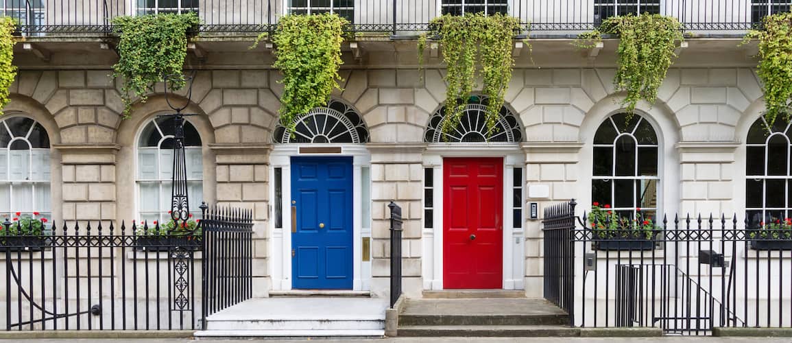 Front view of similar brick houses with red and blue door.