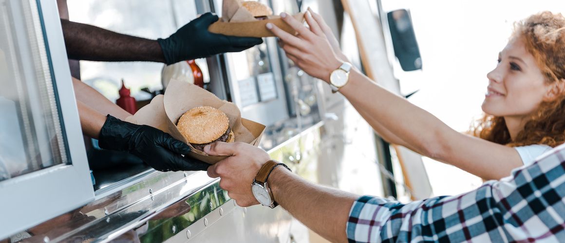 Girl budgeting and grabbing burgers from food truck.