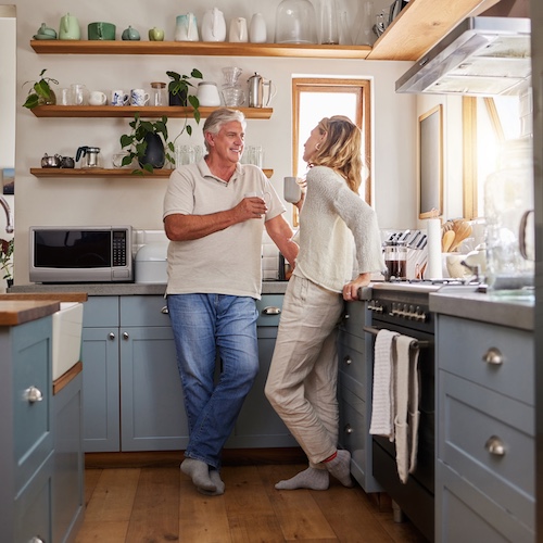 Retired couple having coffee in their kitchen.