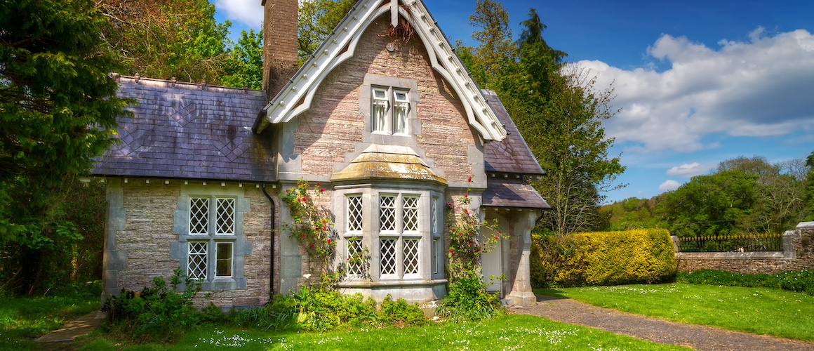 Small cottage home with stone walls, chimney and a front bay window.