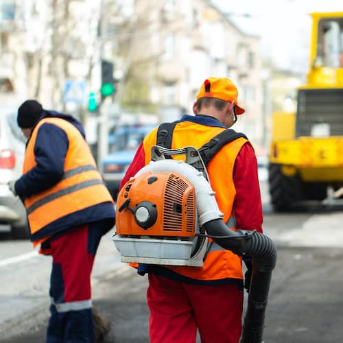 A person using a leaf blower outdoors, representing home maintenance and property care.