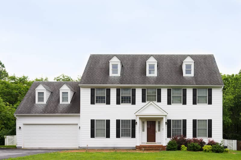 Exterior view of a white colonial style home with black shutters.