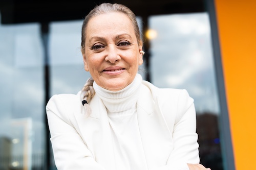 Attorney dressed in white turtleneck and white blazer, smiling at client.