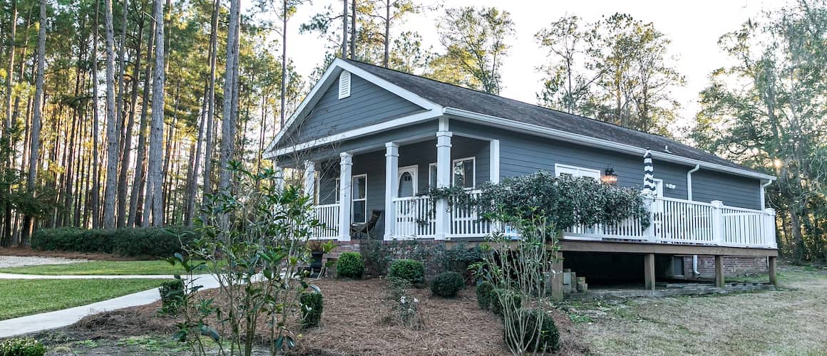 blue gray manufactured home with a wraparound porch and white railing