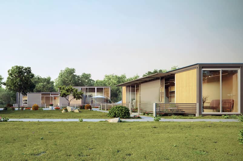 Shipping container home community with three houses around a shared lawn.