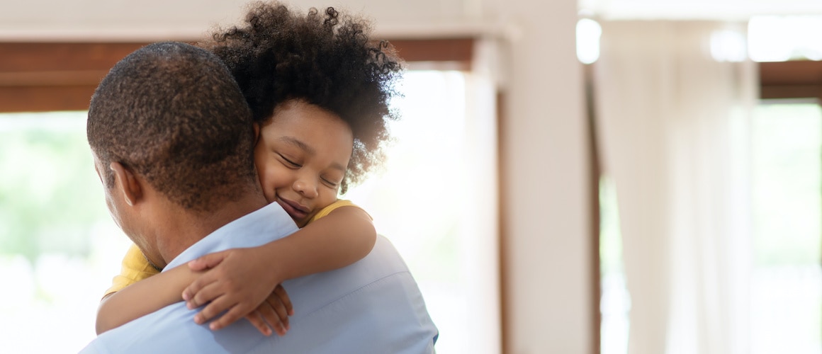 A father hugging his young son, in their home.