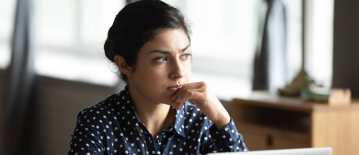 Image of a pensive woman, possibly considering real estate or financial decisions.