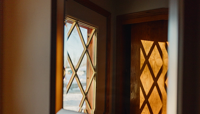 Sun rays coming through diamond shaped door onto wooden interior door, viewed through a mirror.