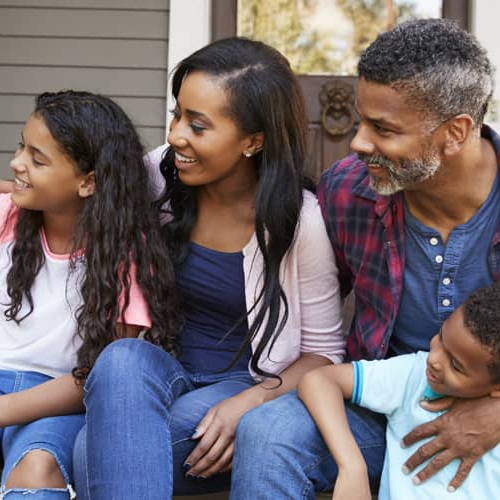 A family sitting on the porch with their pet having enjoyable moment.