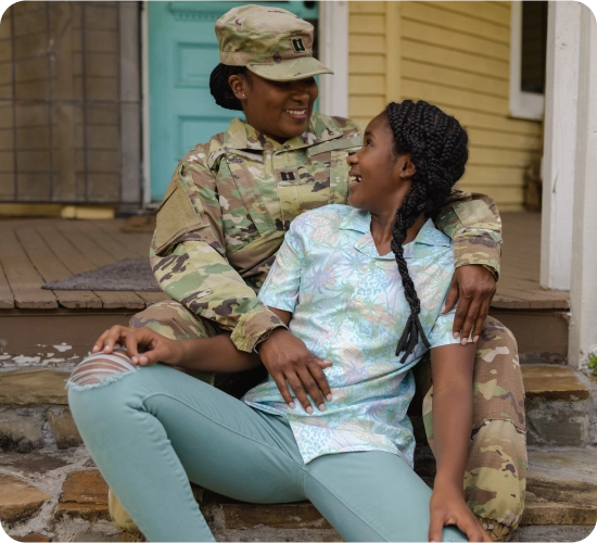 Veteran hugging family member in home with folded American flag in the background.