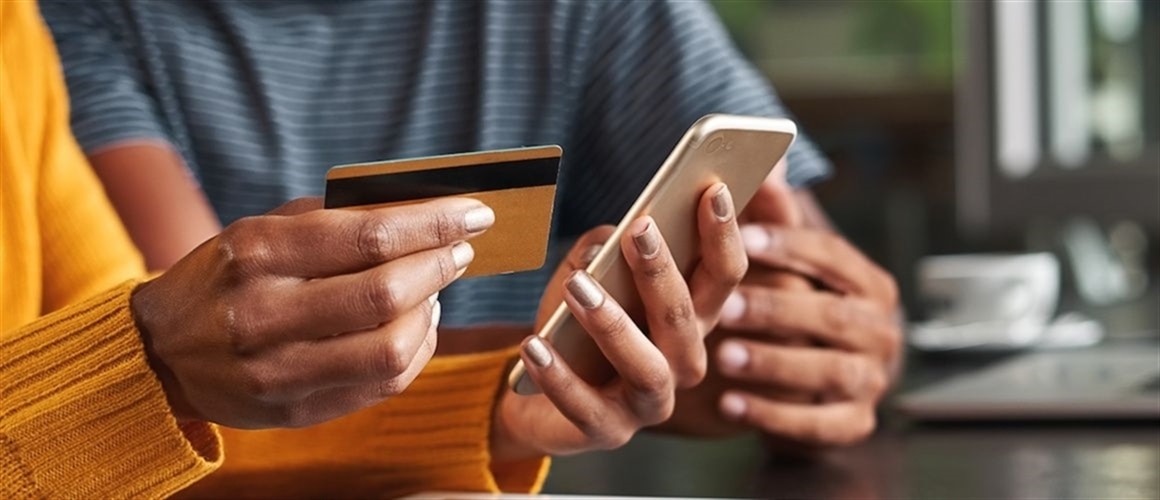 Woman holding credit card and phone, comparing loan options.