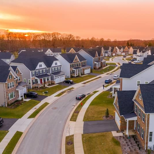 Neighborhood of mcmansion homes with sunset in background.