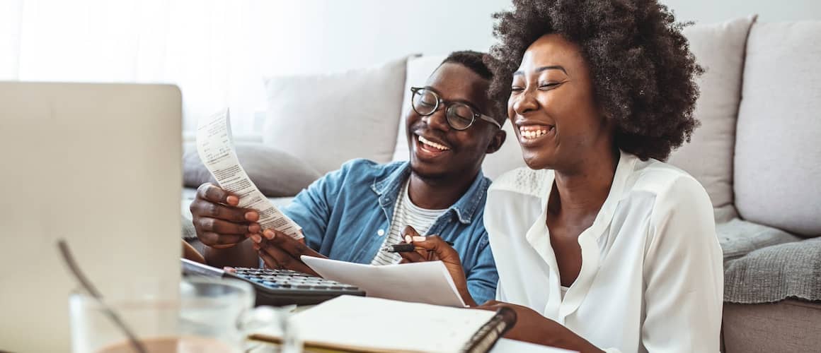 Couple sitting in living room laughing, planning finances.