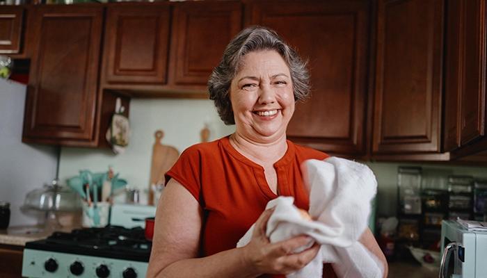 Woman holding white kitchen towel laughing.
