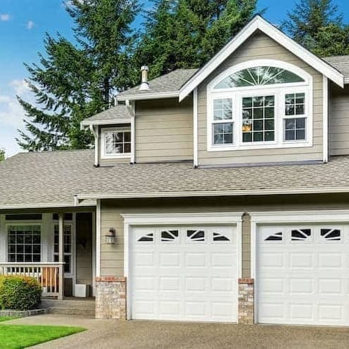A white and grey two storey house with a broad driveway.
