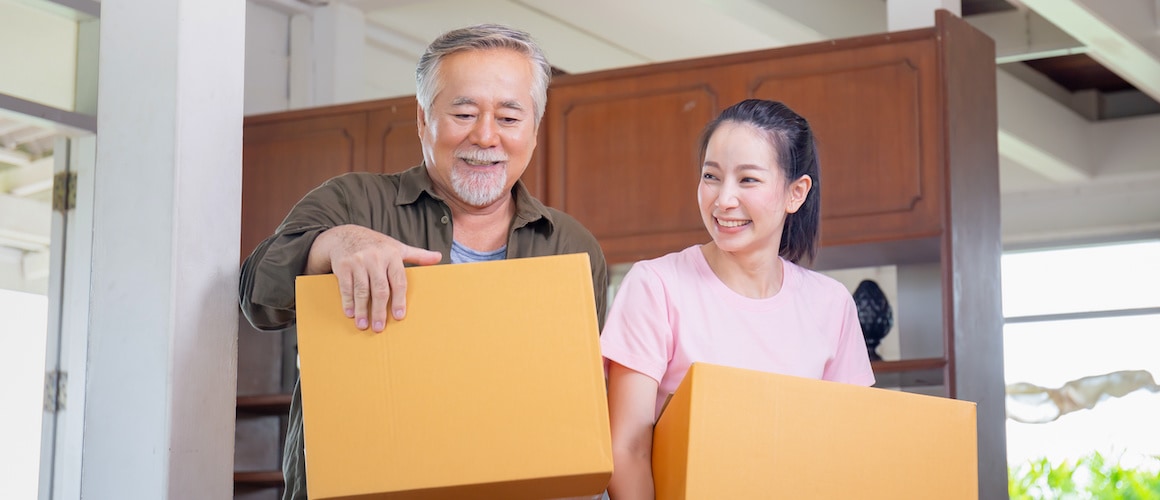 A younger Asian woman moving with a senior father, depicting a family or intergenerational relocation scene.