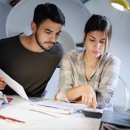 Young couple reviewing invoices and doing family business plan.