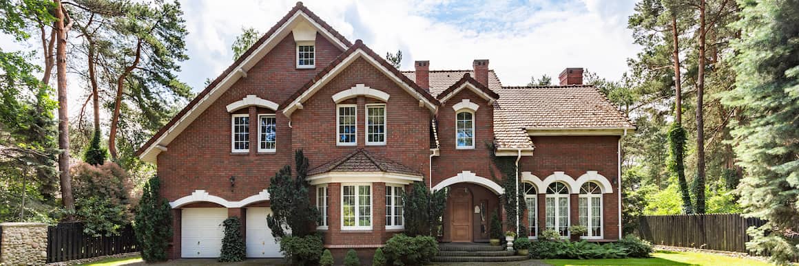 A large brick house surrounded by tall trees.