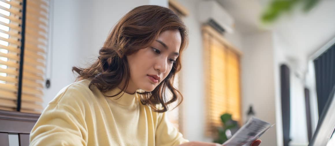 Woman reading documents while sitting in front of the computer.