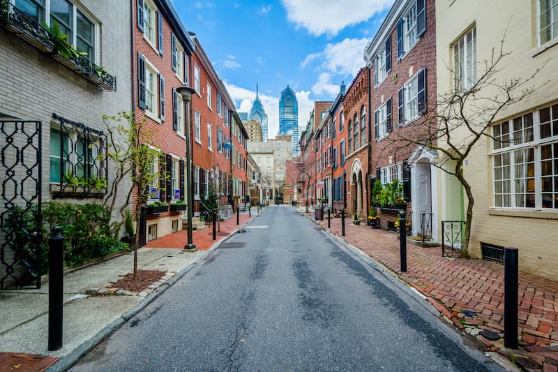 RHB Assets From IGX: Charming brick alley with Philadelphia skyline in the background.