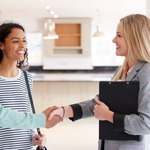 Couple shaking hands with an agent, possibly after finalizing a real estate deal or signing an agreement.