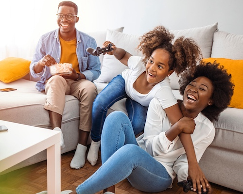 Small family playing video games together while on a couch.