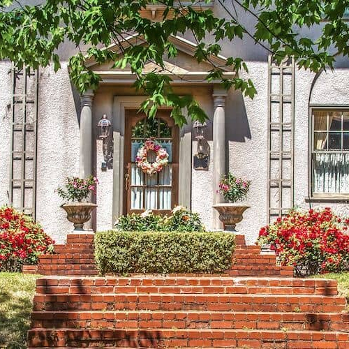 Large regal brick home with white columns and stone stairway.