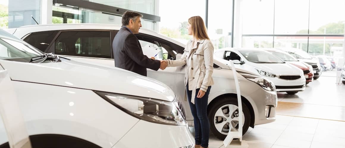 Car salesman shaking hand with woman after selling a car