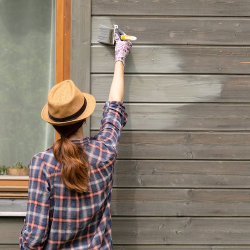 Someone painting the outside of a house, symbolizing sweat equity in home improvement.