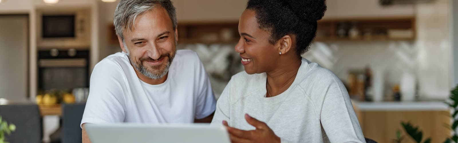 A man and a women looking at the laptop and smiling.
