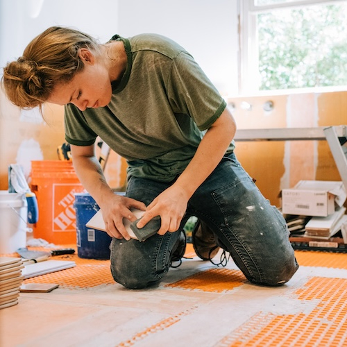 Woman tiling bathroom floor.