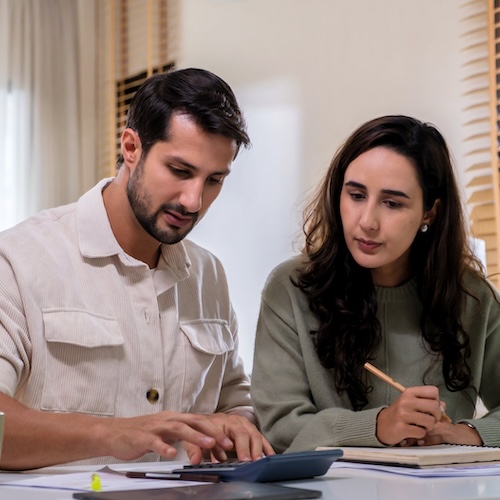 Couple doing paperwork at dining room table.
