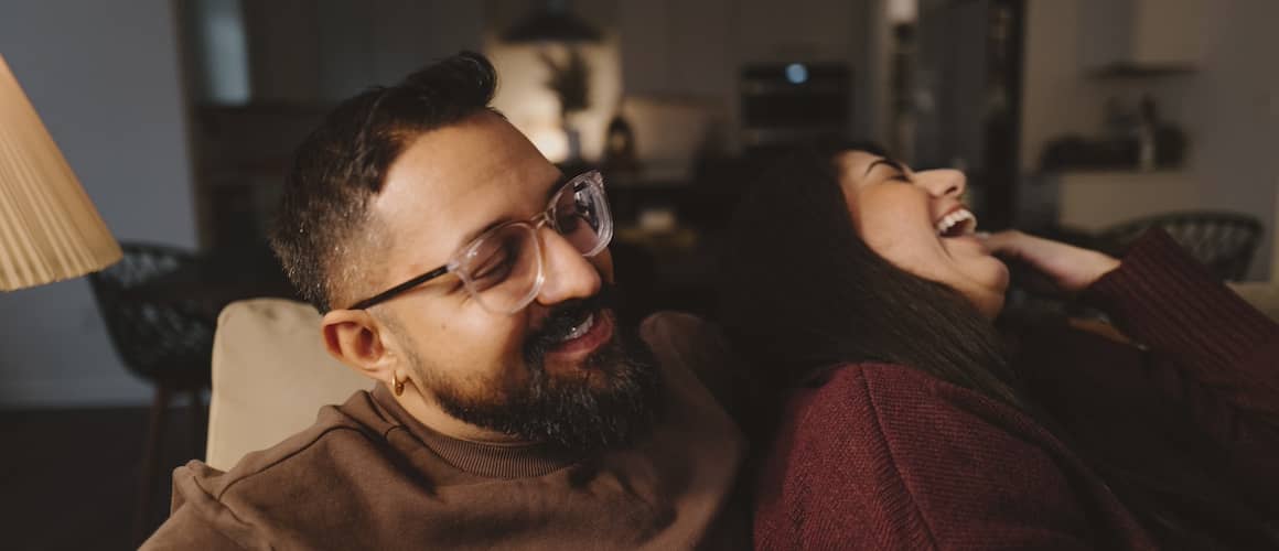 Couple snuggling and laughing together on couch.