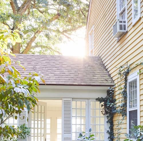 Sun room off of two story home on a sunny day.