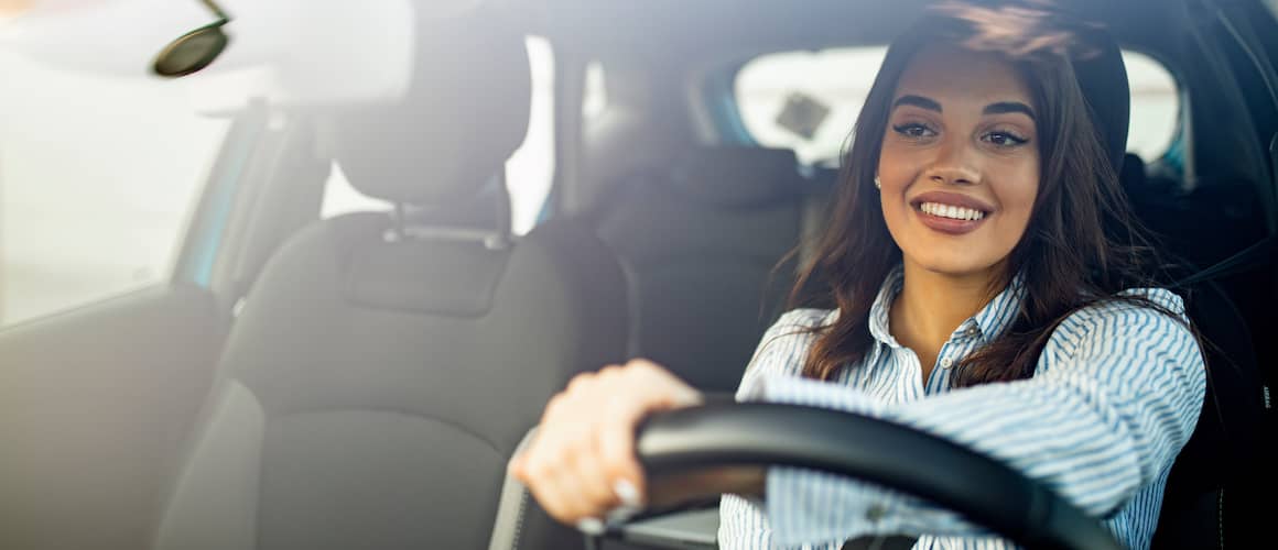 Smiling woman behind wheel of new car.