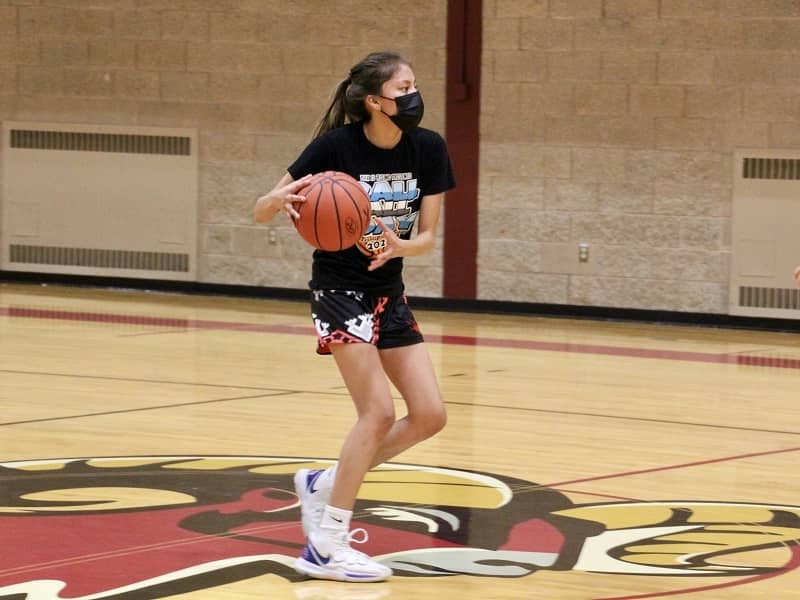 A girl wearing a mask at basketball practice.