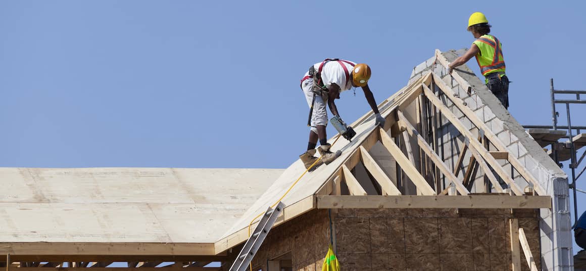 Workers on a building roof, possibly involved in construction or maintenance work.