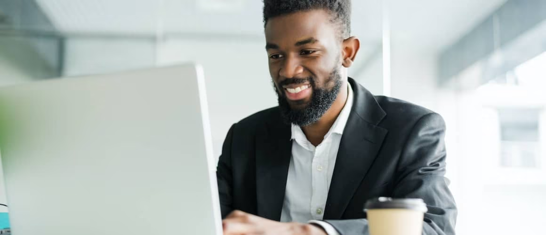 African American smiling while using laptop.