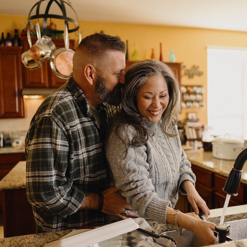 Couple laughing in kitchen.