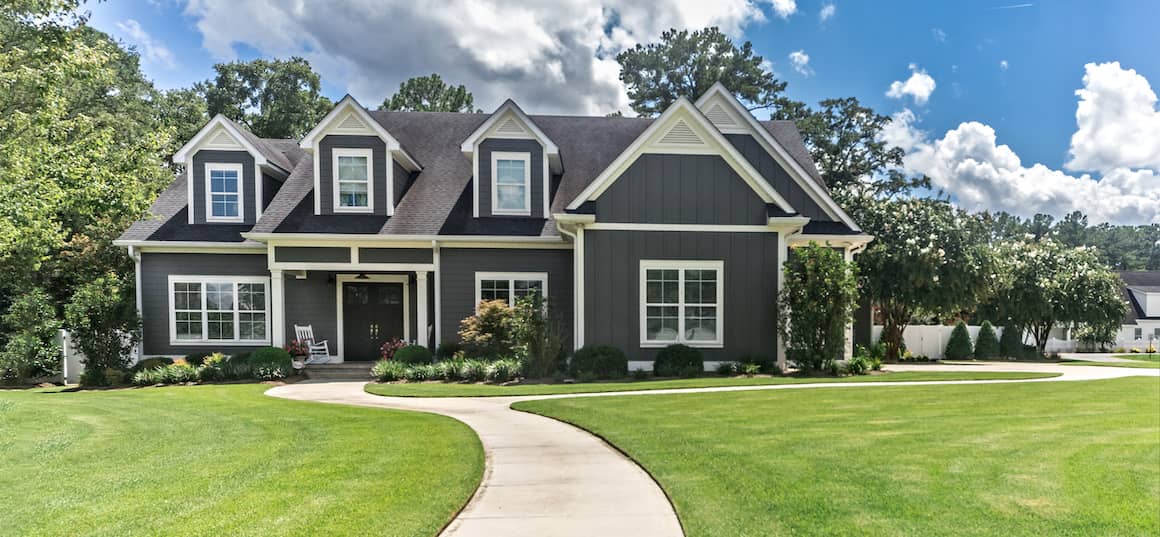 RHB Assets From IGX: Large, gray, newly-constructed home with a front lawn.