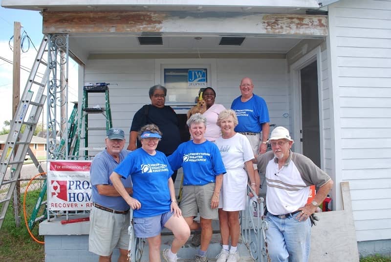 Group of volunteers on front porch smiling. 